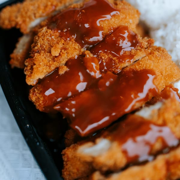 Crispy, breaded chicken katsu slices drizzled with brown sauce, served with white rice.