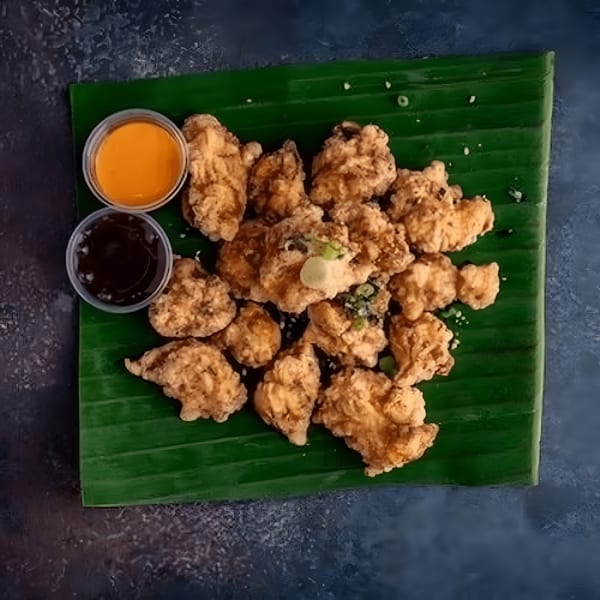 L&L Hawaiian Barbecue's crispy fried chicken pieces with two dipping sauces on a banana leaf.